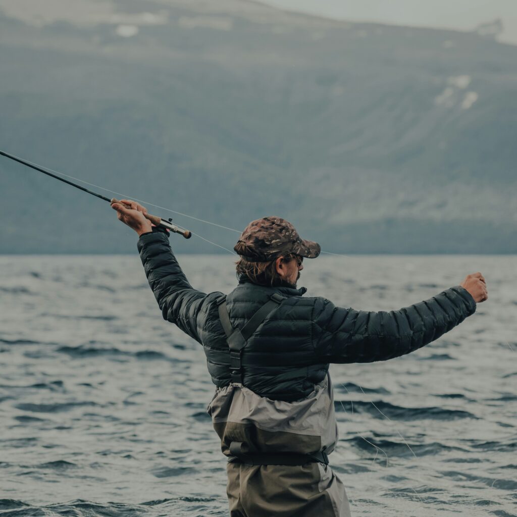 man casting a fly rod standing in the water