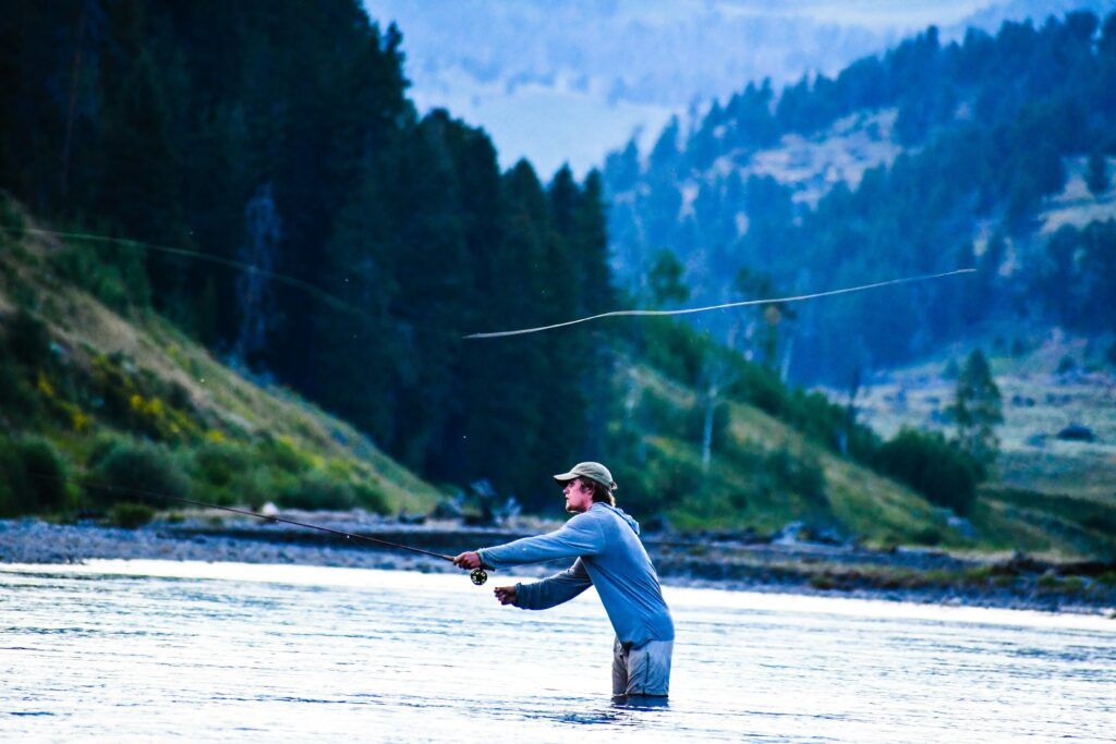 man casting a fly from the middle of the river